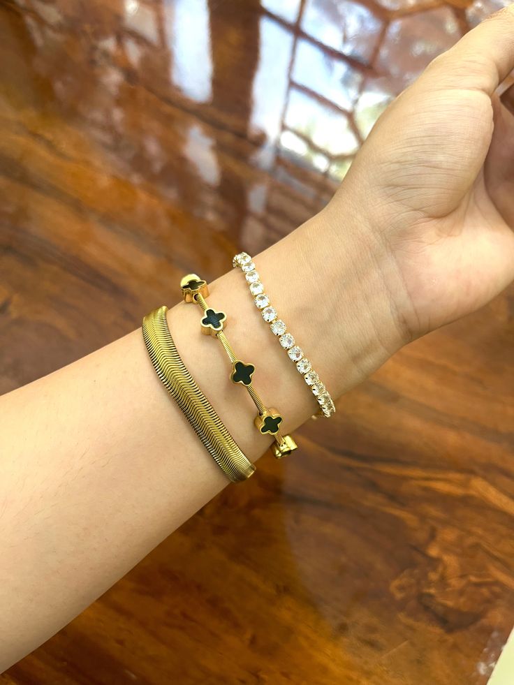 Hand wearing multiple bracelets on a wooden surface