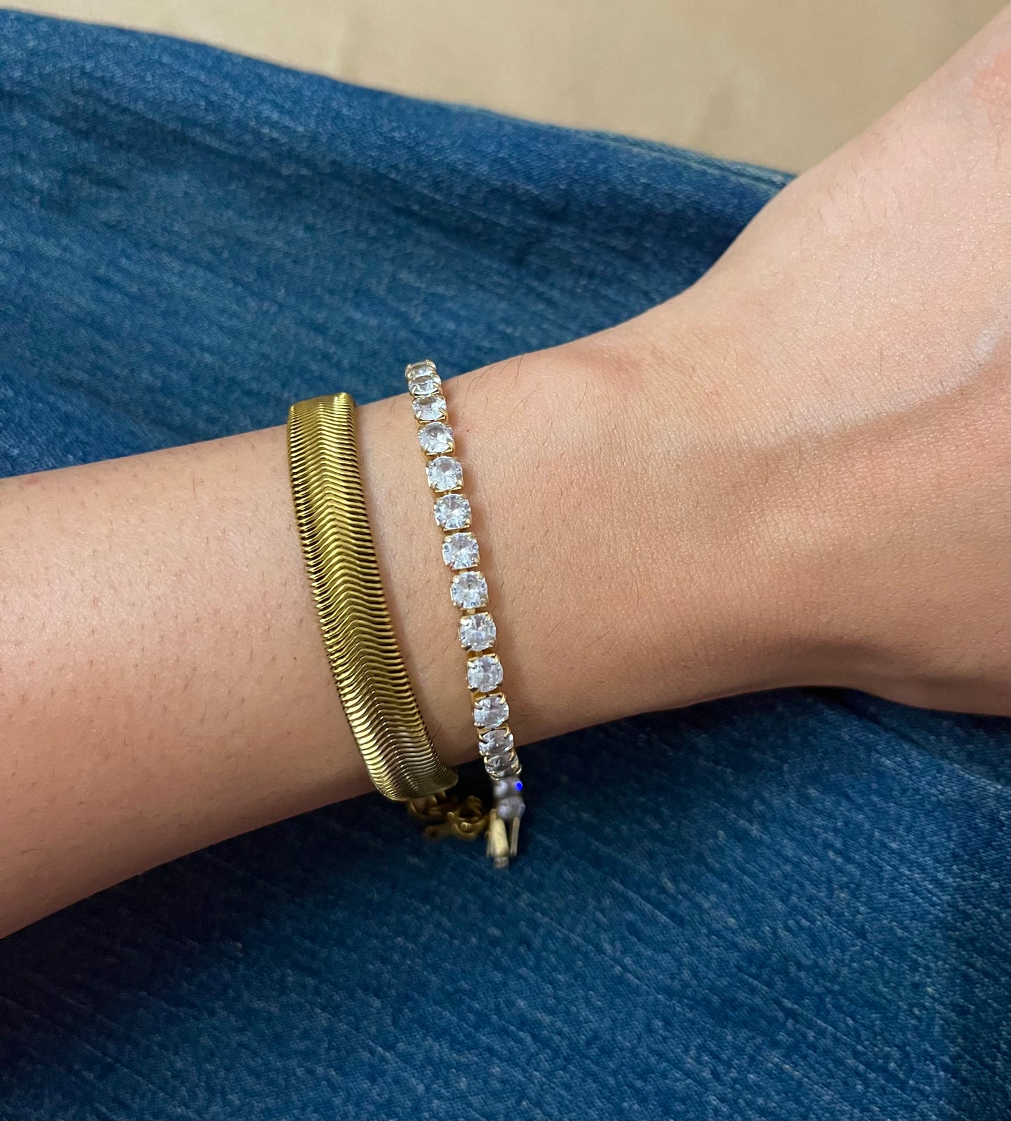 An 18K gold-plated demi-fine stainless steel bracelet stack worn on a person's wrist, featuring two bracelets with one having a link chain design and the other adorned with crystal accents.